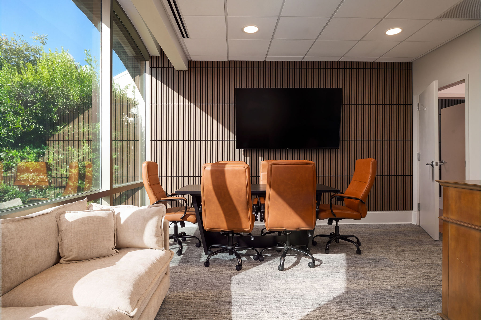 Consultation and meeting room with table, chairs, sofa, and wall screen