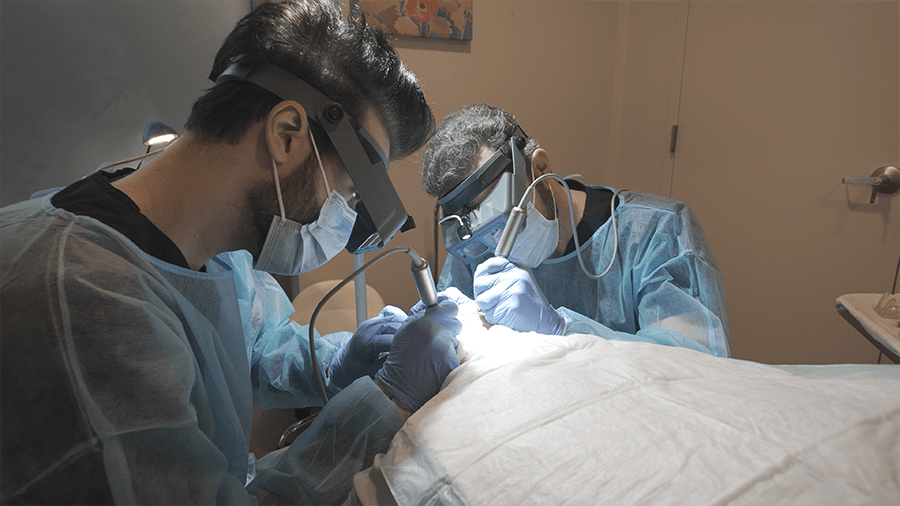 Two Signature Hair Restoration specialists performing a dual-extraction hair transplant